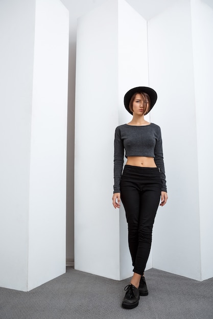 Free photo young beautiful girl in black hat posing over white wall
