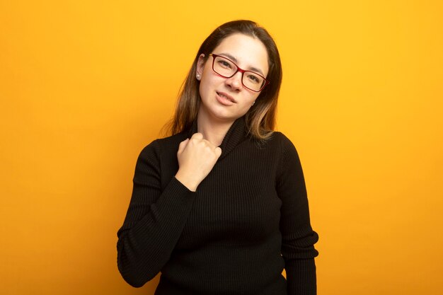 Young beautiful girl in a black turtleneck touching her collar 