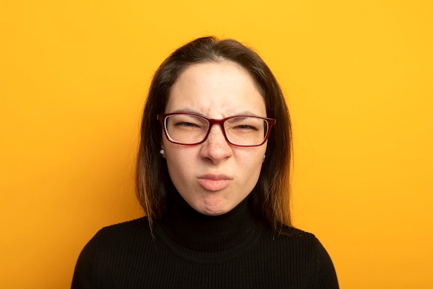 Young beautiful girl in a black turtleneck with annoyed expression being displeased 