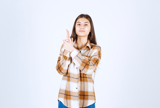 Young beautiful girl in casual outfit standing on white wall. 