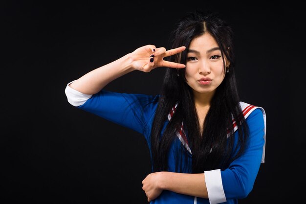 A young beautiful girl dressed in a school uniform shows a victory sign The concept of youth good luck everything will be fine