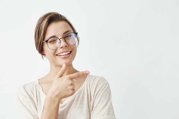 Free Photo young beautiful girl in glasses smiling winking pointing finger in side .