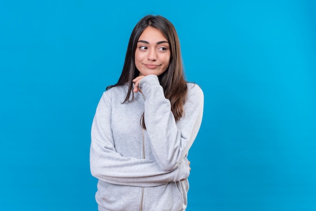 Young beautiful girl in gray hoody looking away with pensive sight