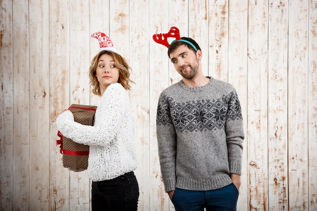 Regalo nascondente di natale della giovane bella ragazza dal suo ragazzo.