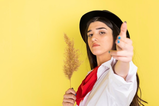 Бесплатное фото Молодая красивая девушка держит ветку пшеницы и направляет руки как пистолет на камеру высококачественное фото