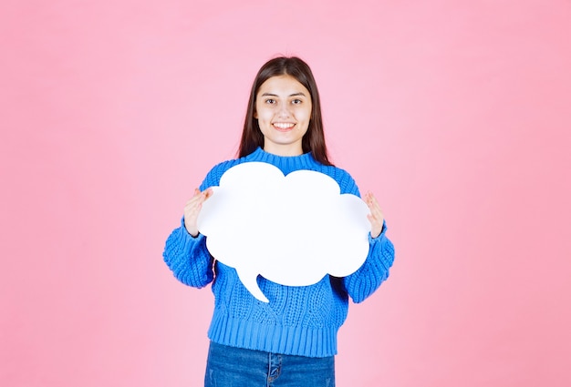 Young beautiful girl holding a white bubble for text on a pink.