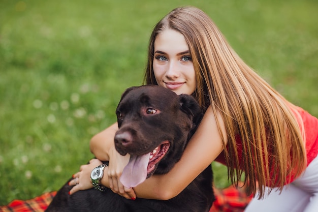 The young beautiful girl hugs her dog in the garden
