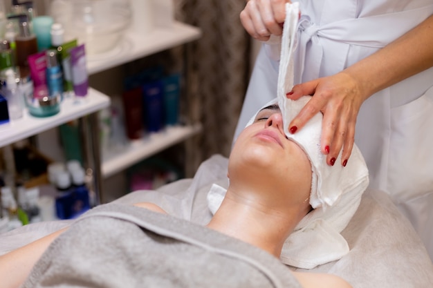 A young beautiful girl lies on the beautician's table and receives procedures, a light facial massage.