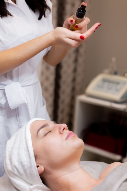 A young beautiful girl lies on the beautician's table and receives procedures, a light facial massage.