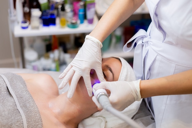 Free photo a young beautiful girl lies on the beautician's table and receives procedures