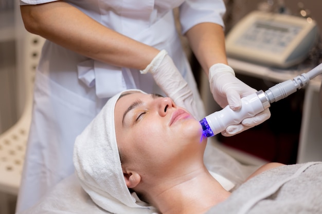 Free photo a young beautiful girl lies on the beautician's table and receives procedures