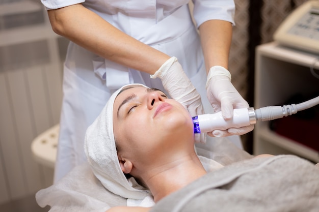 Free photo a young beautiful girl lies on the beautician's table and receives procedures