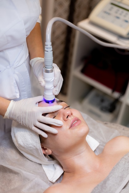 Free photo a young beautiful girl lies on the beautician's table and receives procedures