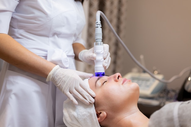 Free photo a young beautiful girl lies on the beautician's table and receives procedures