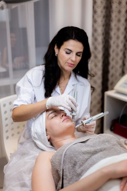 A young beautiful girl lies on the beautician's table and receives procedures