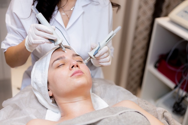 A young beautiful girl lies on the beautician's table and receives procedures