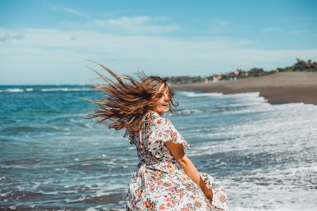 young beautiful girl posing on the beach, ocean, waves, bright sun and tanned skin