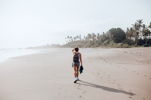 young beautiful girl posing on the beach, ocean, waves, bright sun and tanned skin