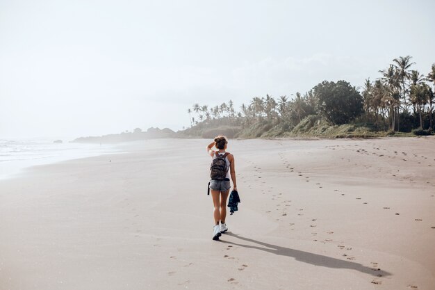 ビーチ、海、波、鮮やかな日差しと日焼けした肌でポーズを取る若い美しい少女