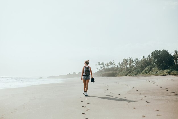 ビーチ、海、波、鮮やかな日差しと日焼けした肌でポーズを取る若い美しい少女