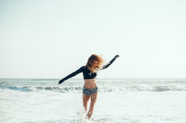 молодая красивая девушка позирует на пляже, океан, волны, яркое солнце и загорелая кожа