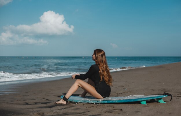 サーフボード、女性サーファー、海の波とビーチでポーズを取る若い美しい少女