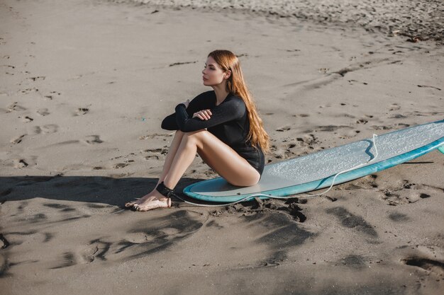 young beautiful girl posing on the beach with a surfboard, woman surfer, ocean waves