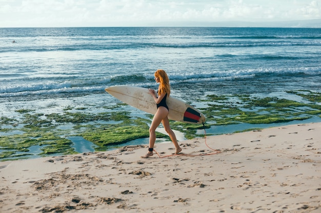 서핑 보드, 여자 서퍼, 파도와 해변에서 포즈 젊은 아름 다운 소녀
