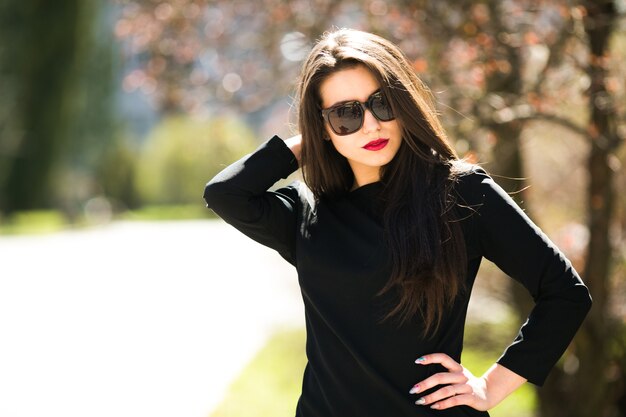 Young beautiful girl posing in a black leather jacket in the park