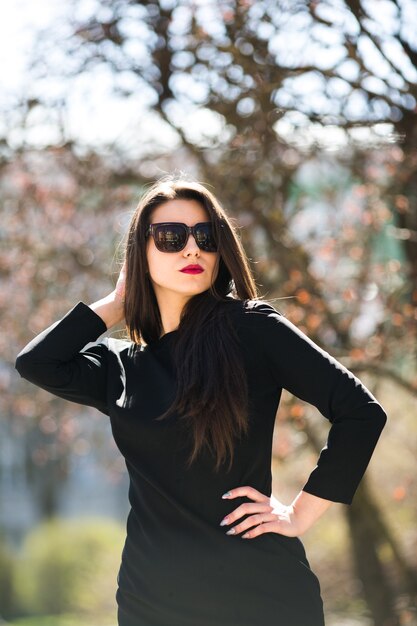 Молодая красивая девушка позирует в черной кожаной куртке в парке