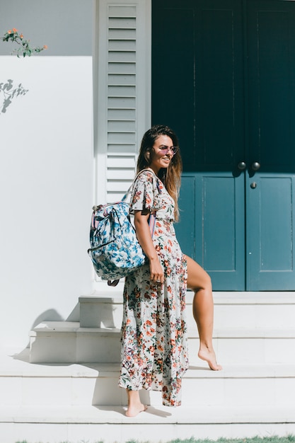 young beautiful girl posing on the street in a dress with a backpack