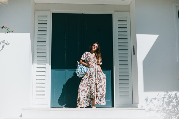 young beautiful girl posing on the street in a dress with a backpack