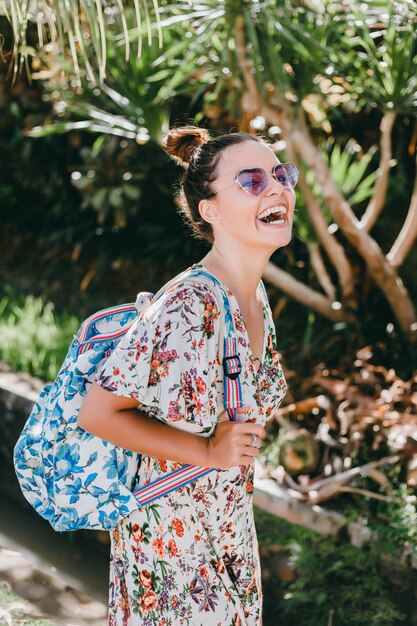 young beautiful girl posing on the street in a dress with a backpack