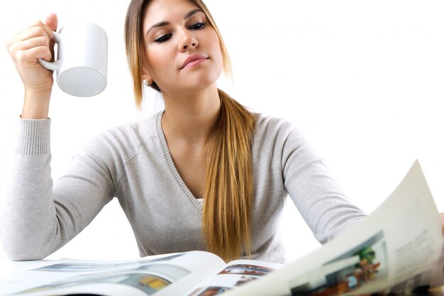 Young beautiful girl reading news and drinking coffee. Isolated