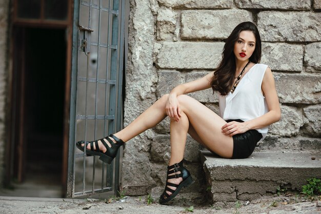 Young and beautiful girl sitting at the door on a stone slab