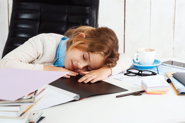 Young beautiful girl sleeping at working place in office.