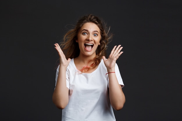 Young beautiful girl smiling rejoicing over grey wall.