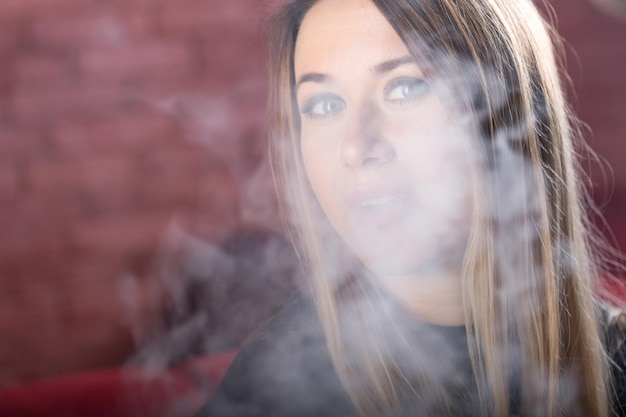 La giovane bella ragazza fuma un narghilè