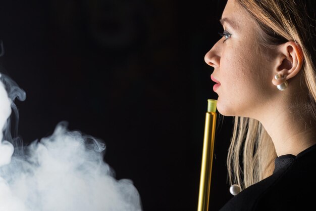 Young beautiful girl smokes a hookah