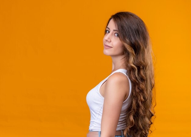 Молодая красивая девушка, стоящая в профиль на изолированной оранжевой стене с копией пространства