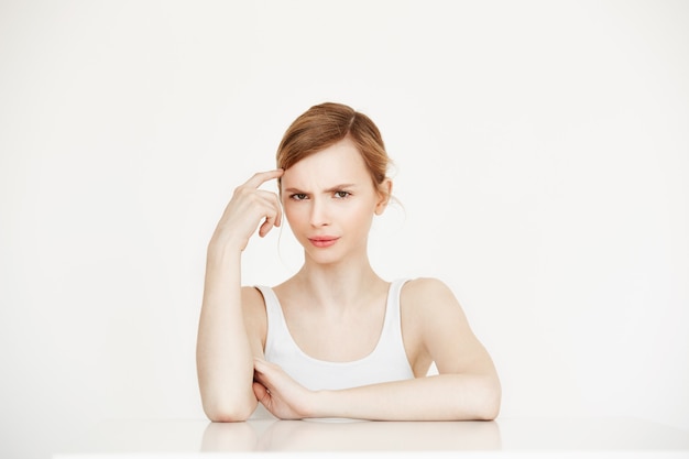 Young beautiful girl thinking sitting at table . Facial treatment.