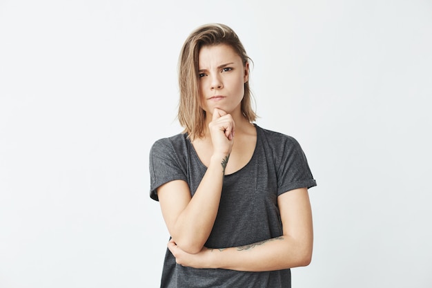 Young beautiful girl thinking with hand on chin frowning .