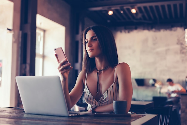 young beautiful girl uses a laptop in cafe, surfing in internet