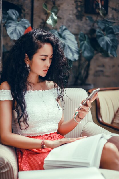 young beautiful girl uses a smartphone on the street, surfing the internet