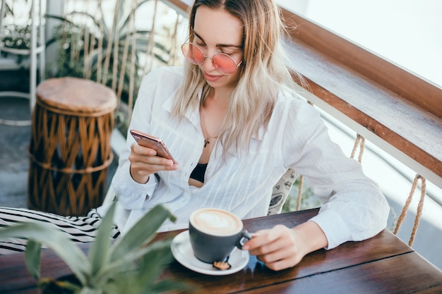 young beautiful girl uses a smartphone on the street, surfing the internet