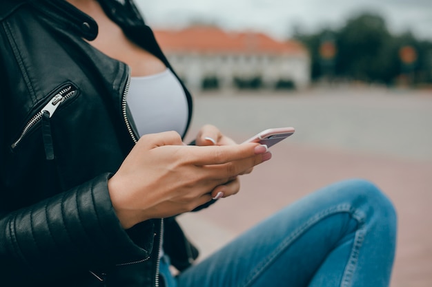 young beautiful girl uses a smartphone on the street, surfing the internet