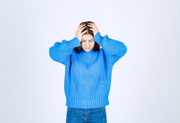 Free photo young beautiful girl wearing blue sweater holding hands on head.