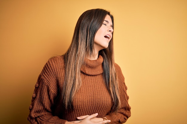 Free photo young beautiful girl wearing casual sweater standing over isolated yellow background with hand on stomach because nausea painful disease feeling unwell ache concept