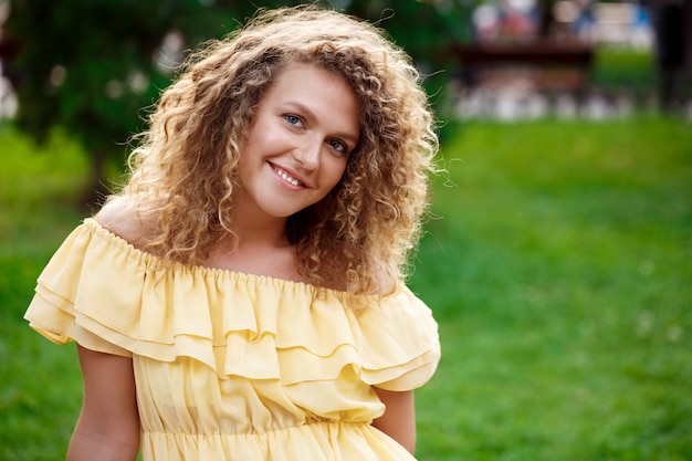 Young beautiful girl in yellow dress sitting on grass.