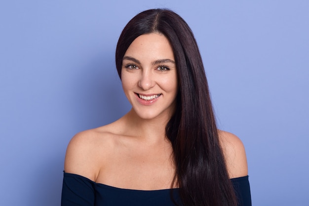 Young beautiful gorgeous young woman with perfect skin wearing dark blue dress posing with bare shoulders